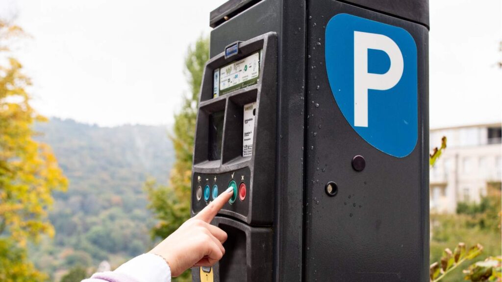 Persona utilizando un parquímetro en zona azul, ejemplo práctico para entender cómo quitar multa zona azul y evitar sanciones por aparcamiento.