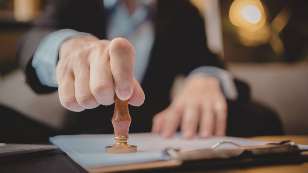 Persona sellando documentos oficiales en una oficina, representando el proceso administrativo para recurrir multas Madrid Central.